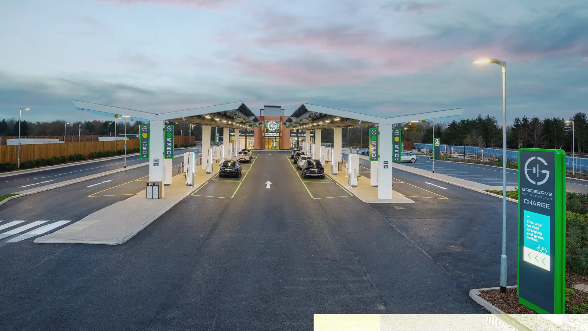 Exterior view of GRIDSERVE’s Electric Forecourt in Braintree with large digital LED screens and EV charging zones by TRISON.