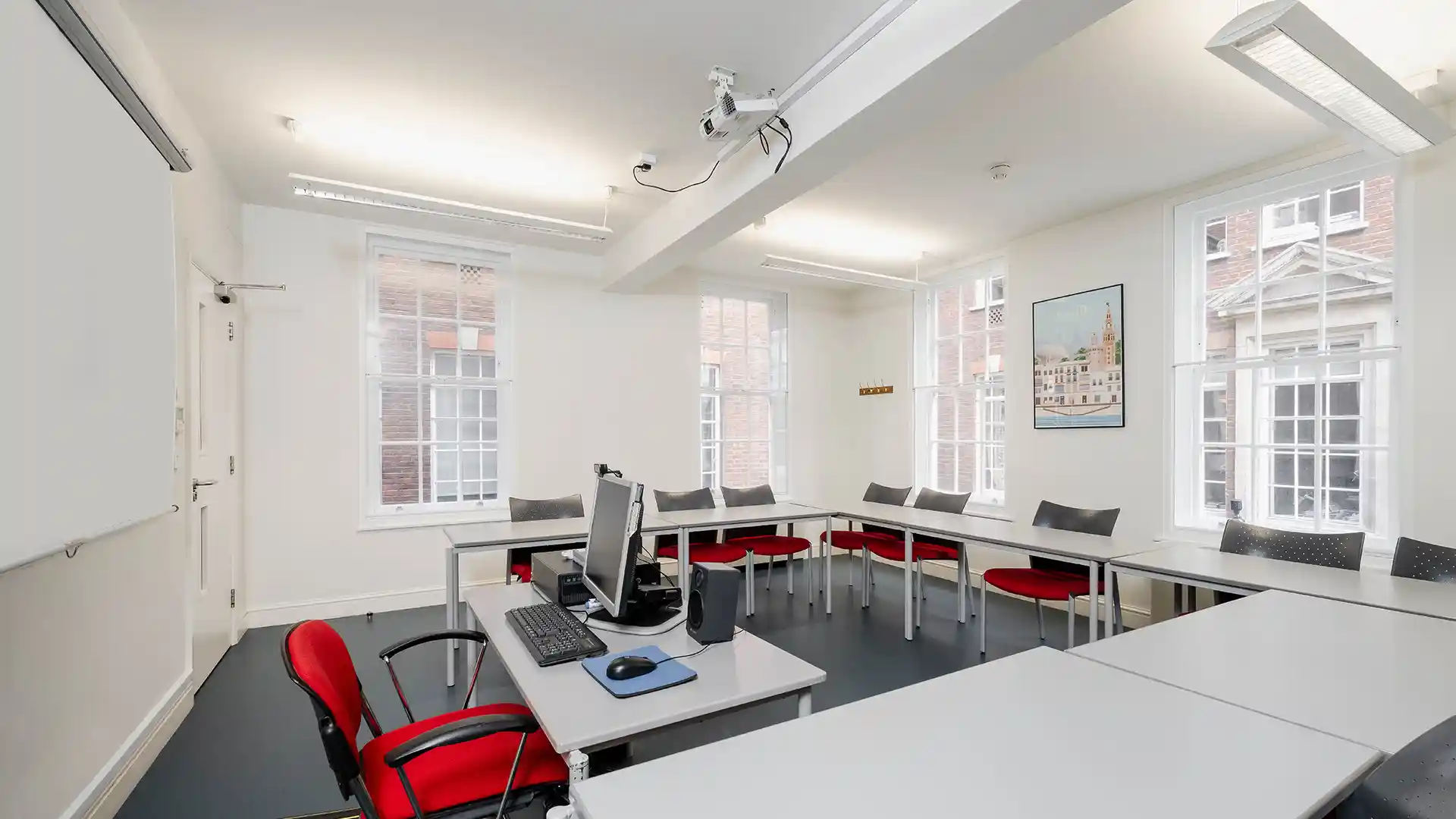 Audiovisual-equipped classroom at Instituto Cervantes featuring ceiling-mounted projector and technology-ready teaching environment.
